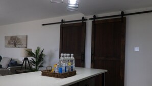 A kitchen with a white countertop, a basket of bottled water, and a potted plant.