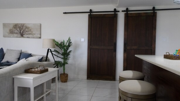 A living room with a sofa, a coffee table, a lamp, a potted plant, and a sliding door.