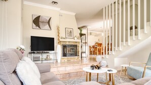 Una sala de estar con chimenea, televisor y escalera.