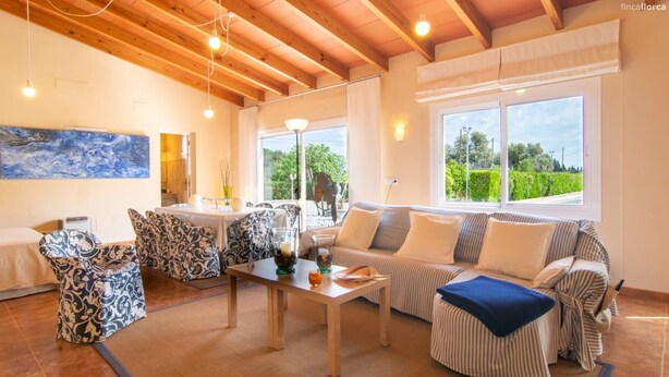 A cozy living room with a sofa, chairs, a table, and a painting on the wall.