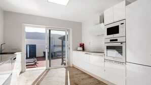 Eine moderne Küche mit weißen Schränken, einem eingebauten Backofen und einer Glastür zum Patio.