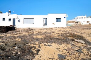 Un edificio blanco con techo plano, un ventanal y una puerta.