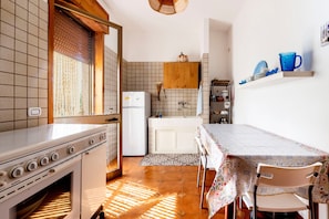 Cocina compacta con estufa, refrigerador y una mesa de comedor con sillas.