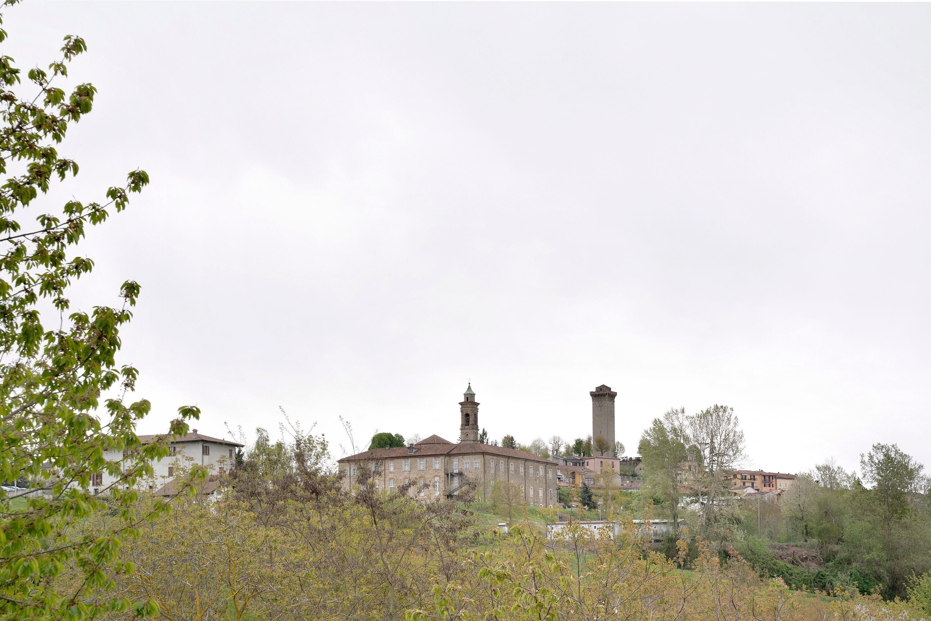 A historic building with a prominent tower, surrounded by trees and other structures.