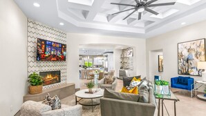 A modern living room with a fireplace, comfortable seating, a dining area, and a kitchen in the background. - Cinema+Golf S’m+P P’g +Volley+Basket+Pickle+G’room (Bermuda Dunes)
