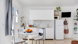 Cocina compacta con comedor, lavadora, microondas y televisión.