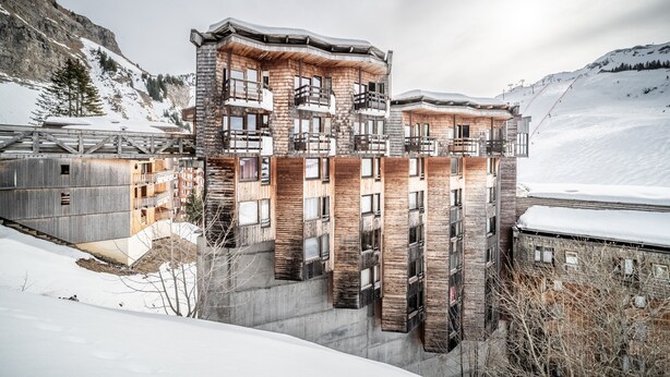 Un hotel de varios pisos con un diseño arquitectónico único, que presenta paneles de madera y balcones.