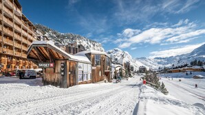Un centro de esquí con edificios de madera, un telesilla y montañas nevadas al fondo.