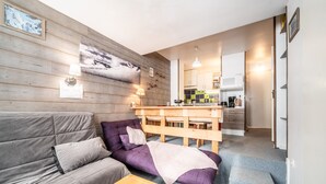 Una sala moderna con un sofá, una mesa de centro y una cocina al fondo.
