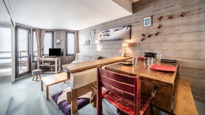 Una habitación acogedora con una mesa de comedor de madera, un sofá, un televisor y una ventana con cortinas.