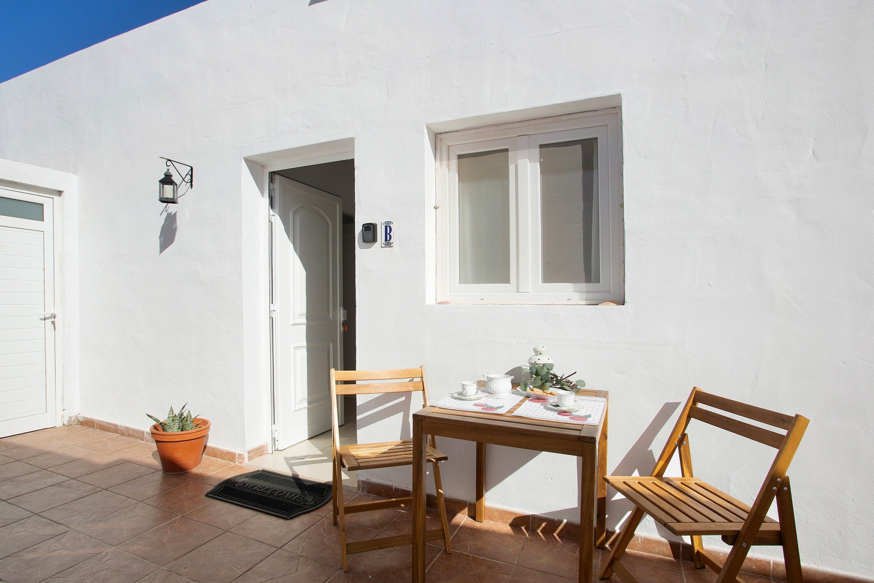 Un edificio blanco con una puerta, una ventana y una mesa con sillas.