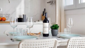 Uma mesa de jantar com uma garrafa de vinho, copos, pratos e uma pequena planta em vaso.