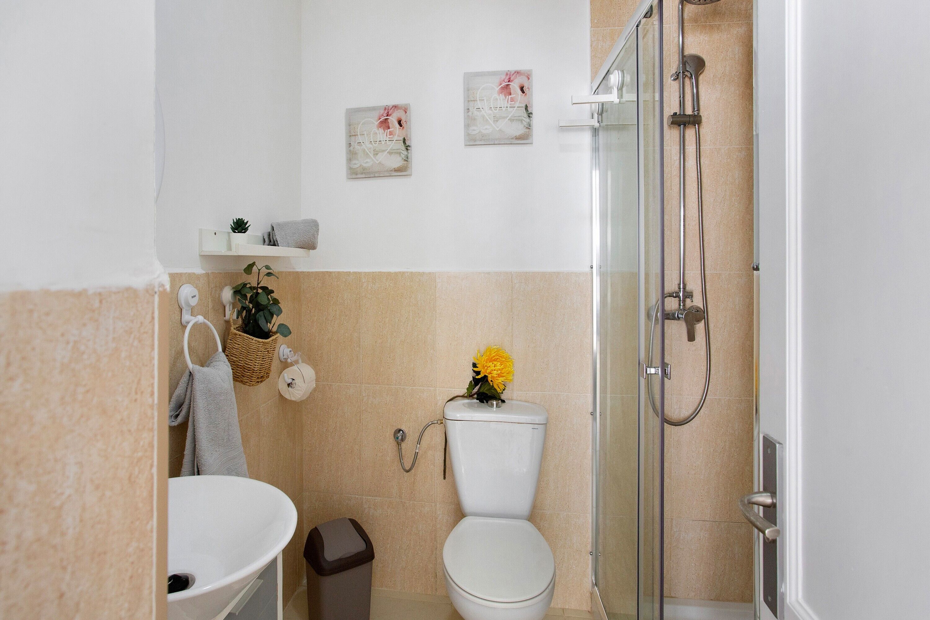 Un baño con lavamanos, inodoro, ducha y decoración en la pared.