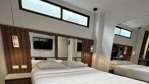 Ein modernes Schlafzimmer mit einem großen Bett, einem an der Wand montierten Fernseher und einem Fenster über dem Bett.