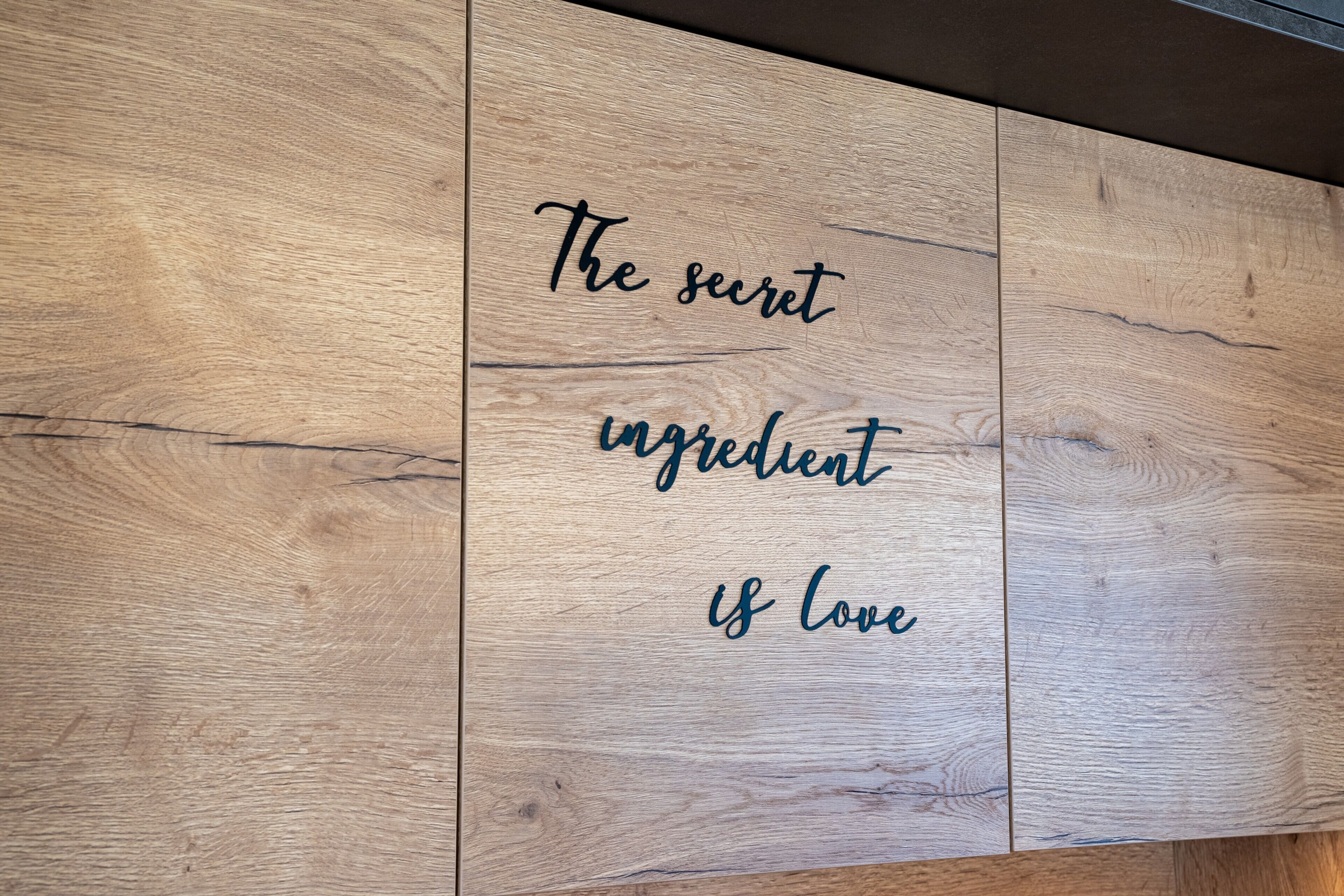 Ein Holzbrett mit dem Text 'The secret ingredient is love'.