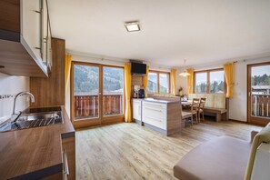 Une cuisine moderne dotée d’un évier encastré, de planchers en bois et d’un coin repas avec un banc et des chaises.