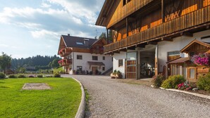 A wooden building with a gravel driveway and a grassy area.