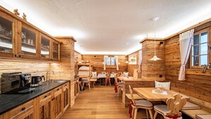 A wooden cabin interior with a kitchen, dining area, and a loft bedroom.
