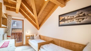 Une pièce avec des poutres en bois, un lit, un bureau et une fenêtre donnant sur les montagnes.