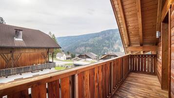 A wooden balcony with a view of houses and mountains.