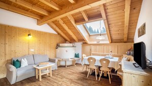 Un intérieur en bois avec un plafond mansardé, un canapé, une table à manger avec des chaises et un téléviseur.