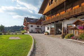 A traditional wooden building with a gravel driveway, a grassy area, and a clear sky.