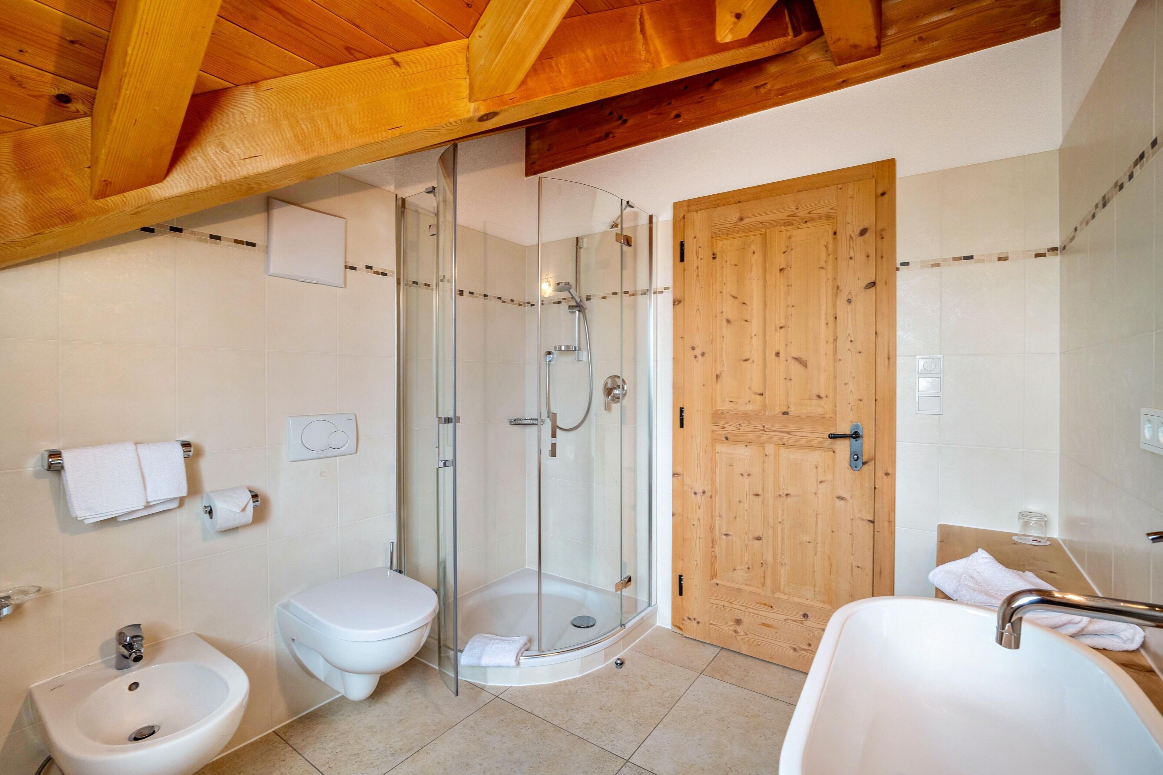 Une salle de bain avec une douche à parois de verre, une porte en bois, un lavabo et des toilettes.