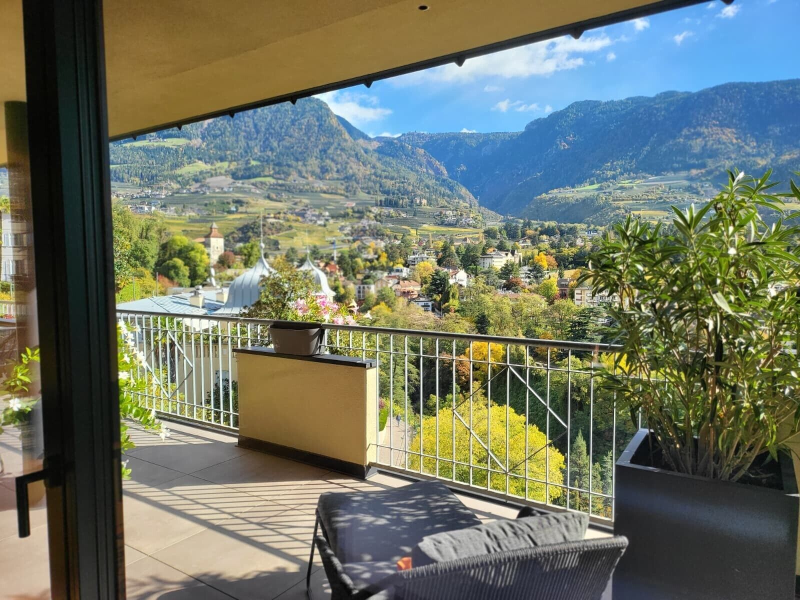 A balcony with a view of a valley, a chair, and potted plants.