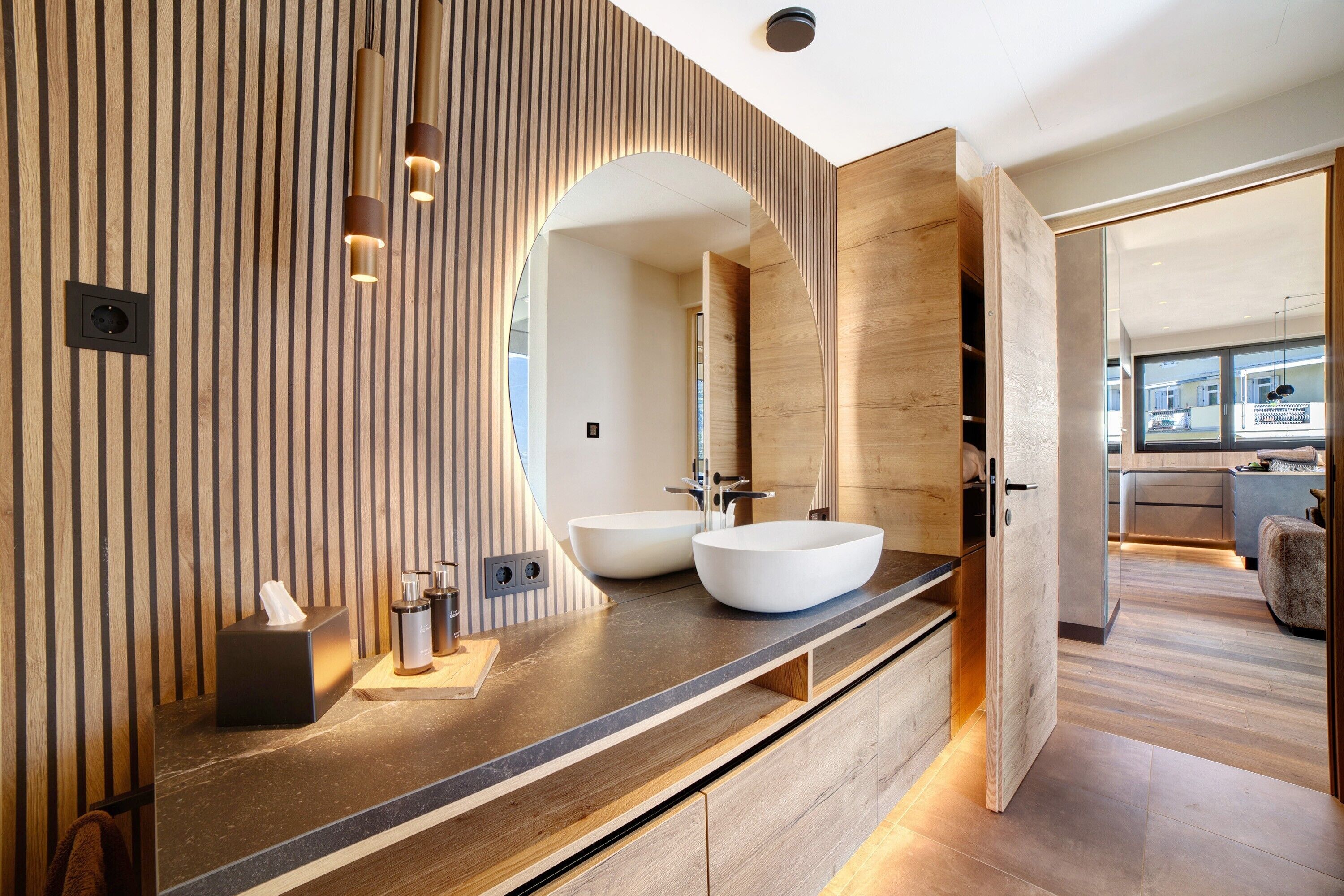 A modern bathroom with a wooden vanity, two sinks, and a large mirror.
