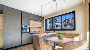 Une cuisine moderne dotée d’un grand îlot central, de meubles en bois et offrant une vue sur la ville grâce à de grandes fenêtres.