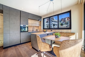 Une cuisine moderne dotée d’un grand îlot central, de meubles en bois et offrant une vue sur la ville grâce à de grandes fenêtres.
