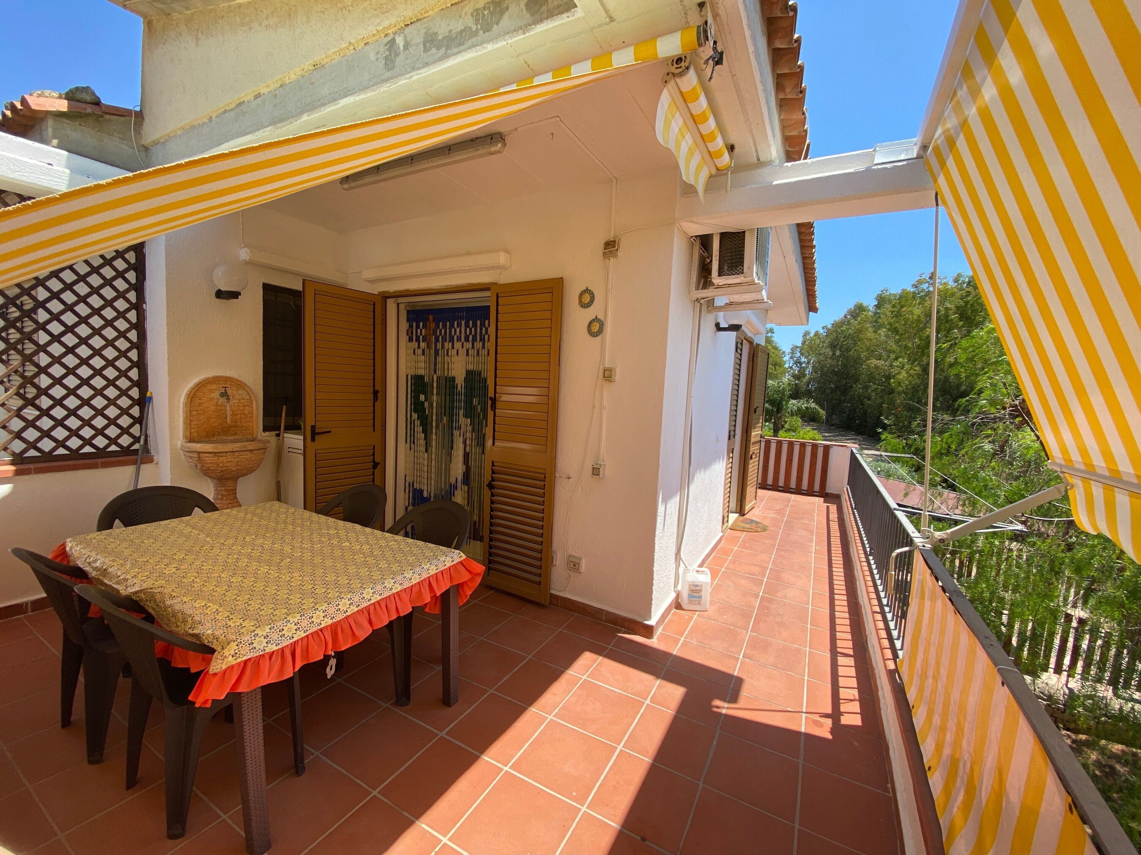 Une terrasse avec une table et des chaises, une fontaine et une vue sur la verdure.