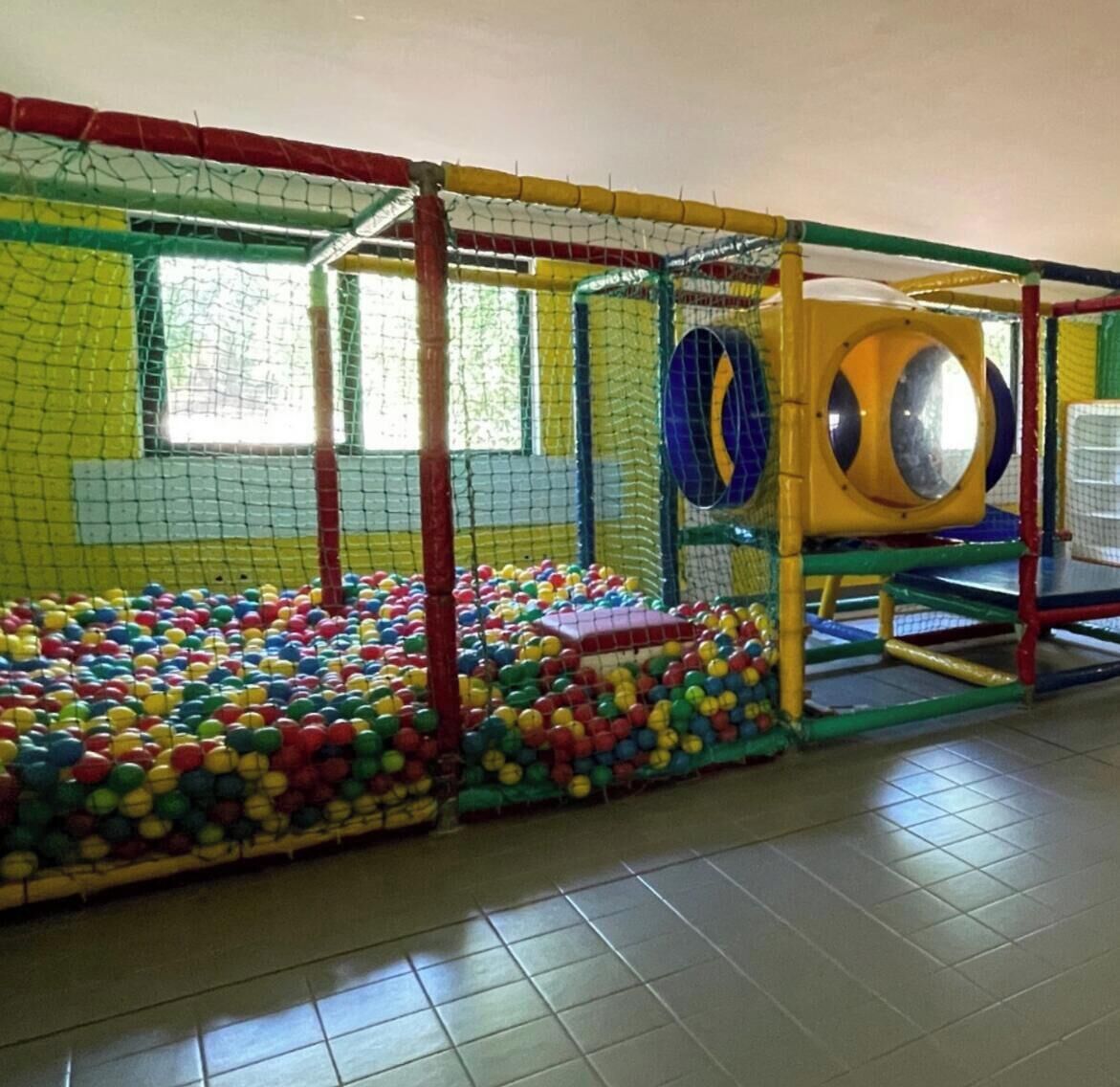 A play area with a ball pit, climbing structures, and a slide.