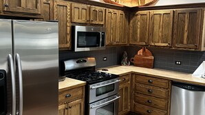 A modern kitchen with wooden cabinets, stainless steel appliances, and a patterned rug.