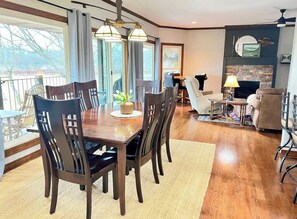 Un comedor espacioso con suficiente espacio para hasta 15 personas, que cuenta con una mesa grande y sillas, una chimenea y vistas al exterior.