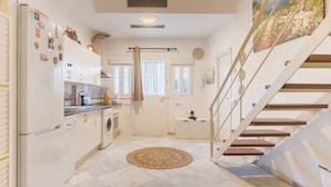 A kitchen with a refrigerator, oven, and sink; a staircase with wooden steps; and a window with curtains. - Exclusive Duplex Penthouse with Private Terrace in the Heart of Seville (Sevilla)
