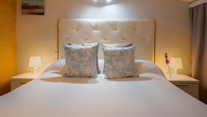A hotel room with a large bed, two nightstands, a wall-mounted lamp, and a painting. - Exclusive Duplex Penthouse with Private Terrace in the Heart of Seville (Sevilla)