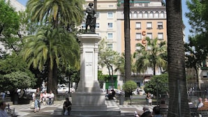 A public square with a statue, palm trees, and a building with balconies in the background. - Exclusive Duplex Penthouse with Private Terrace in the Heart of Seville (Sevilla)