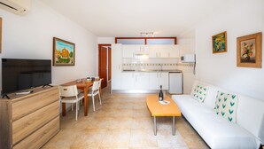 Un salon comprenant un téléviseur, un canapé, une table basse et un coin repas.