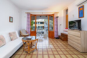 Une pièce comprenant un canapé, une table à manger avec des chaises, un téléviseur et un meuble en bois.