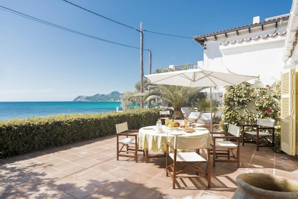 An outdoor patio with a table set for dining, overlooking a coastal view.