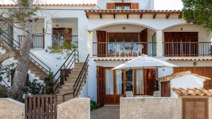 A two-story building with a staircase, wooden shutters, and a balcony with outdoor furniture. - Holiday Apartment "Mhm 3" with Balcony & Wi-Fi (Cala Ratjada)