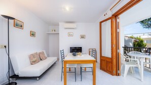 A modern living room with a white sofa, a dining table, and chairs, a TV, and a balcony with outdoor furniture. - Holiday Apartment "Mhm 3" with Balcony & Wi-Fi (Cala Ratjada)