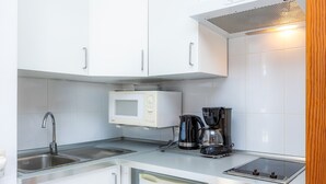 A modern kitchen with a microwave, coffee maker, sink, and built-in oven. - Holiday Apartment "Mhm 3" with Balcony & Wi-Fi (Cala Ratjada)