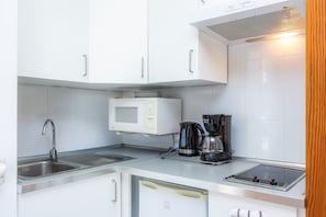 A modern kitchen with a microwave, coffee maker, sink, and built-in oven.