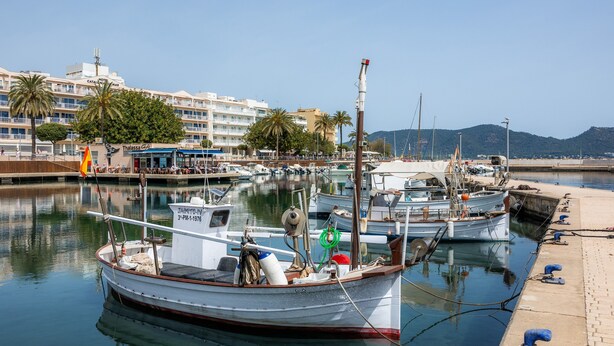 Un port de plaisance avec des bateaux amarrés, un immeuble doté de balcons et un ciel dégagé.