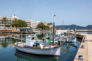 Un port de plaisance avec des bateaux amarrés, un immeuble doté de balcons et un ciel dégagé.