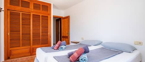 Een hotelkamer met twee bedden, houten kasten, een plafondlamp en een stopcontact aan de muur.
