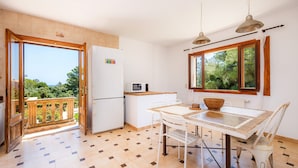 Eine Küche mit Esstisch, Stühlen, einem Kühlschrank und einer Mikrowelle.