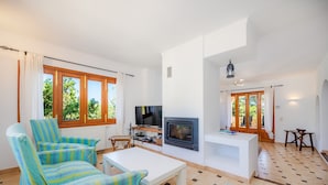 Ein Wohnzimmer mit gestreiften Sesseln, einem weißen Couchtisch, einem Fernseher und einem Kamin.